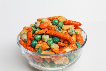 Mixed peanut and snacks, on transparent glass bowl, isolated on white background