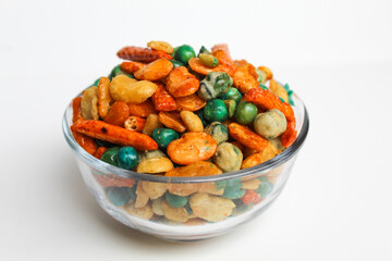 Mixed peanut and snacks, on transparent glass bowl, isolated on white background
