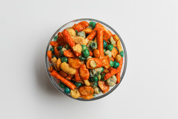 Mixed peanut and snacks, on transparent glass bowl, isolated on white background, flat lay or top view