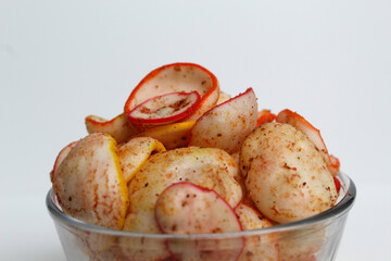 Kerupuk seblak, is colorful round crackers with spicy chili powder topping. In transparent glass bowl, isolated on white background