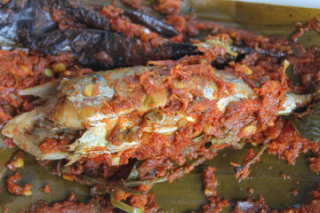 Pepes ikan pedas, or grilled fish with red chili and herbs, wrapped in banana leaf. Indonesia traditional food. Isolated on white background