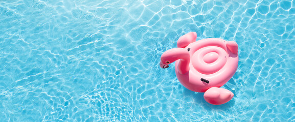 Pink flamingo inflatable ring in sunny pool