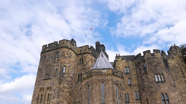 British Flag Waving on Top of Alnwick Medieval Castle, England UK, Low Angle Slow Motion