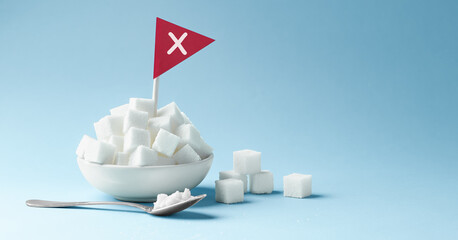 Sugar cubes in white bowl with stop sign, unhealthy warning on blue background