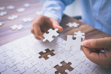 Closeup hand of woman connecting jigsaw puzzle. Business solutions, success and strategy concept.