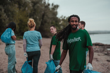 Volunteer collecting trash smiles for the camera as his colleagues clean