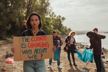 Woman holding a sign about climate change on earth day cleanup