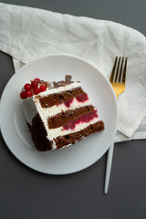 A slice of red velvet cake on a table with a white cloth and a golden fork