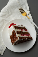 A slice of red velvet cake on a table with a white cloth and a golden fork