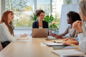 Businesswomen talking and smiling during a meeting inside of the glass office
