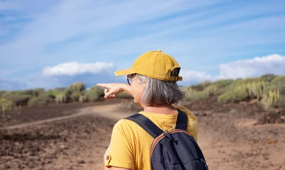 Photo sur Plexiglas les îles Canaries Rear view carefree senior woman in yellow walking in outdoor footpath in a sunny day. Weekend tourism and people leisure outdoor activity concept lifestyle.