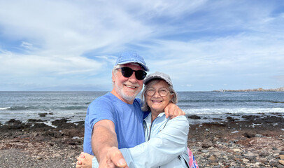 Portrait of happy active senior caucasian couple together in outdoors at the sea beach enjoying vacation and retirement