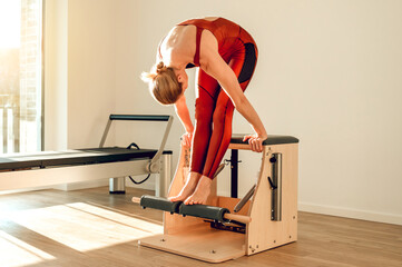 Attractive slim woman training her sporty body on the Pilates machine