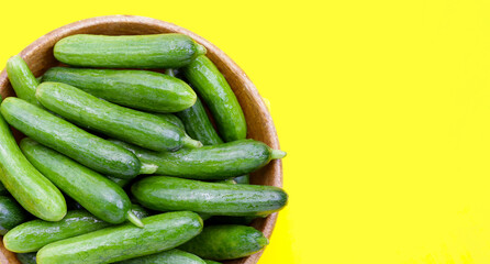 Mini cucumbers on yellow background.