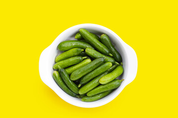 Mini cucumbers on yellow background.