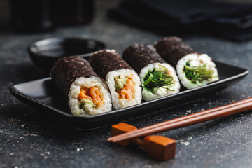Black Plate With Sushi, bowl of soy sauce and Chopsticks