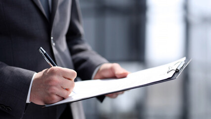 A businessman signs documents in his hands in close-up in the office