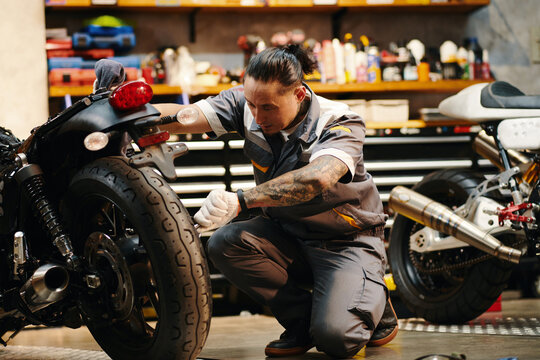 Mechanic in overall changing motorcycle tires