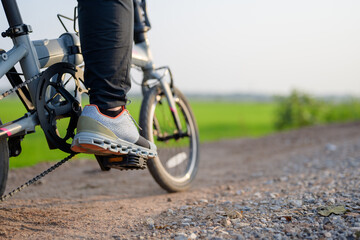 Closeup foot of the bicycle rider on the pedal while riding on the gravel and dirt road in...