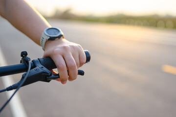 Hand of a woman using her fingers to hold the brake while riding a bicycle on the country road at...