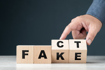 Naklejka premium Fact or Fake concept by alphabet wood cubes, with hand flip some blocks to change the different words
