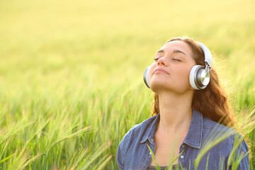 Woman meditating listening guided tutorial in nature - 755437977