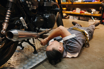 Fototapeta na wymiar Garage worker fixing bottom part of motorcycle