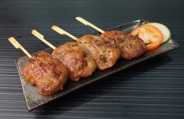 thai bbq grilled tender pork chop meat with sauce in plate on dark grey wood table asian dim sum...