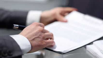 Businessman in close-up working at a desk in the office and signing a contract