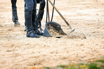 Rider with horse collecting horse manure with the Äppelboy, close-up of the bin and the shovel.