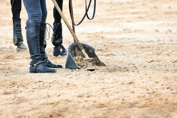 Rider with horse collecting horse manure with the Äppelboy, close-up of the bin and the shovel.