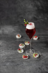 red cocktail glass with ice cubes on dark stone background