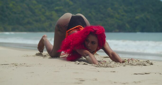 Amidst the pristine white sands of a Caribbean beach, a girl with red hair showcases her bikini.