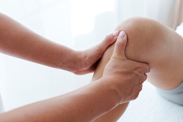 Physical therapist doing chiropractic adjustment on leg of patient in treatment room