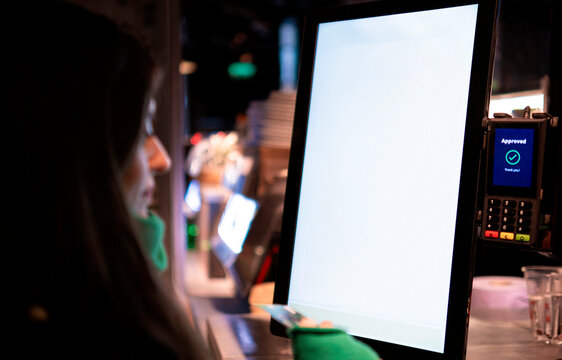 Woman with credit card ordering food on kiosk at cafe