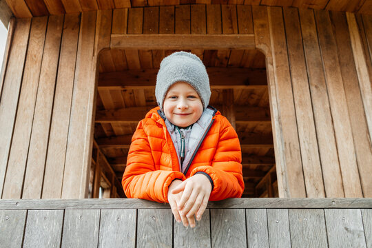 Smiling boy leaning on wooden railing at cabin