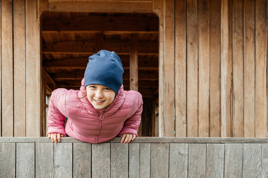 Smiling girl leaning on wooden railing at cabin
