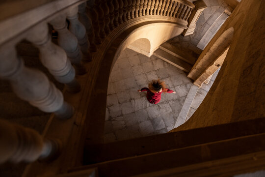 Young woman dancing near stairs in building