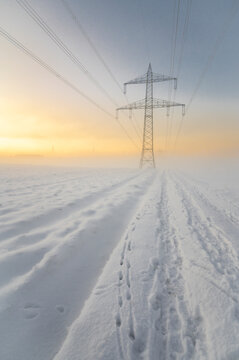 Germany, Hesse, Hunfelden, Snow in front of Electricity Pylon at dawn