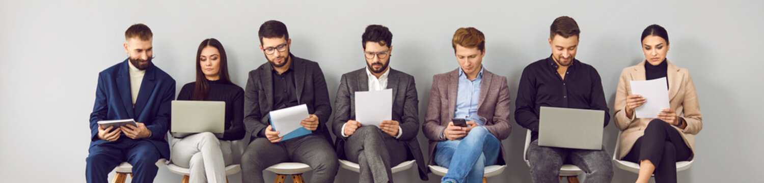 Different people are sitting in row waiting for their turn for interview for position in office or for business meeting about their project. People read resumes and review documents. Web banner.