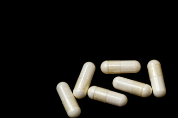 White capsules, pills on a black background with place for text. Medicine, healthcare concept. Range of pharmaceutical drugs