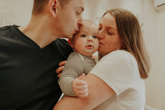 Parents kissing baby boy at home