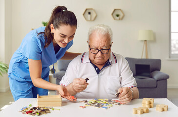 Nurse in geriatric clinic or retirement home helping patient with alphabet puzzle. Senior man...