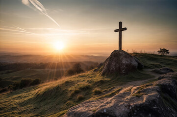 Cross on the top of a hill with sunrise in the background.