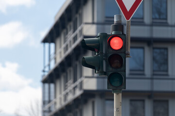 Red traffic light on street building background