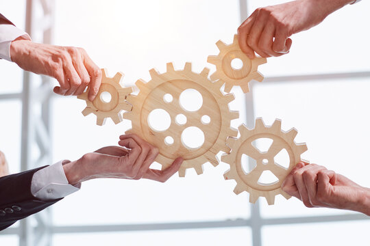Hands of people office workers business partners making common picture of wooden gears on table, selective focus