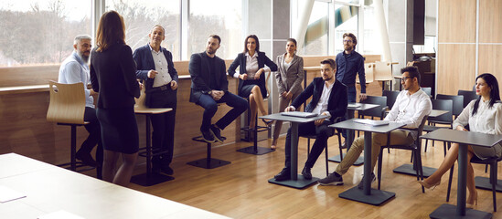 Professional smart business woman conducts training seminar for diverse business people. Diverse...