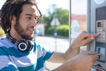 young man paying ticket on parking meter