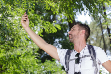 male hiker holding smartphone in the air