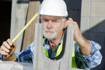 construction worker using a tape measure on concrete block wall